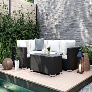 Comfort Garden Bahamas -oleskeluryhmä, jossa musta runko ja valkoiset pehmusteet, sijoitettu puuterassille vihreän seinustan äärelle