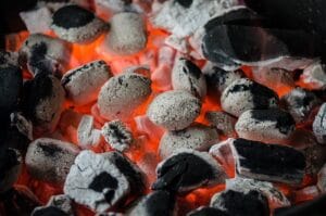 Hehkuvat grillihiilet grillausvalmiina, kuvastaen tehokasta hiiligrillin sytytystä.