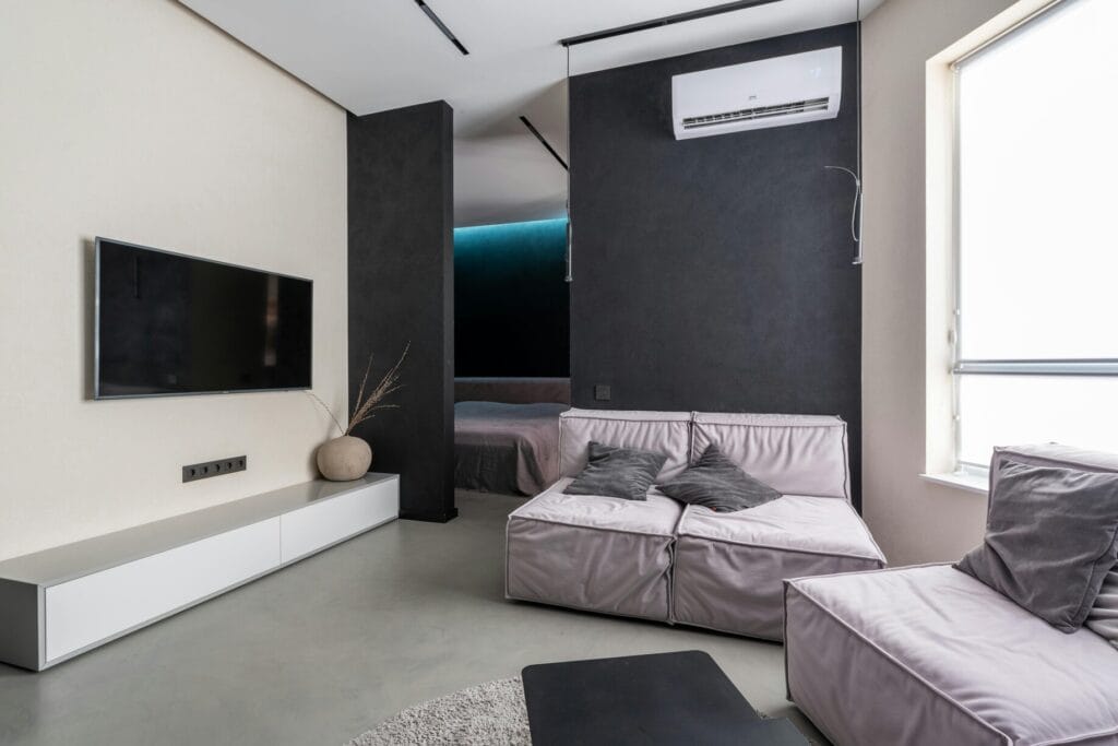 Moderni kerrostaloasunto, jossa seinälle asennettu ilmastointilaite. Tyylikäs sisustus ja tehokas viilennysratkaisu