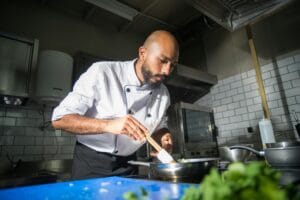 Ammattikokki valmistaa ruokaa keittiössä tarkasti keskittyen. Sous vide -kypsennys auttaa saavuttamaan täydellisen lopputuloksen.