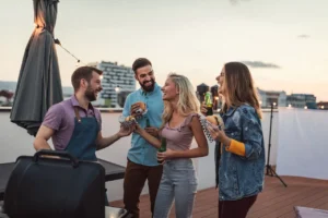 Ystäväporukka grillaamassa parvekkeella sähkögrillin äärellä.