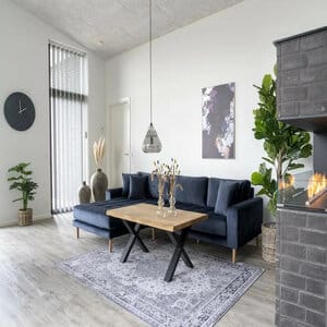 House Nordic Lido tummansininen divaanisohva vasenkätisenä, modernissa olohuoneessa takan ja koristekasvien kanssa