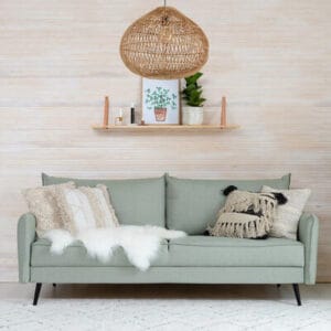 Vaaleanvihreä Art 3-istuttava vuodesohva koristetyynyillä, seinähylly ja rottinkivalaisin taustalla