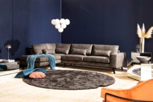 Copenhagen 4-istuttava L-muotoinen divaanisohva tummalla keinonahkalla siniseinäisessä olohuoneessa – moderni ja tilava sohvaratkaisu