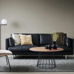 Haga 3-istuttava musta nahkasohva vaaleanruskealla matolla ja minimalistisella sisustuksella – skandinaavinen tyyli ja selkeä muotoilu