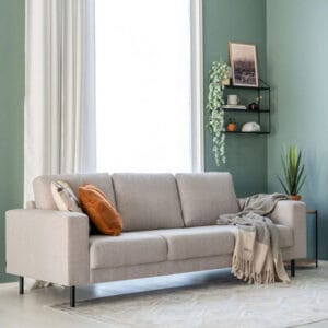 Kairo 3-istuttava vaaleanbeige kangassohva modernissa olohuoneessa, koristetyynyillä ja torkkupeitolla