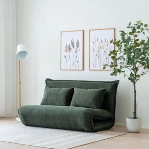 Miska 2-istuttava vihreä futon-vuodesohva valoisassa olohuoneessa, vierellä viherkasvi ja minimalistinen sisustus