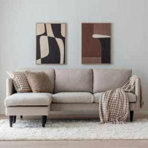 Suvi beige divaanisohva olohuoneessa, taustalla modernit taulut ja pehmeä matto – minimalistinen ja kodikas tunnelma