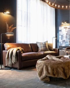 Viscount 2-istuttava ruskea vintage-nahkasohva tyylikkäässä olohuoneessa, jossa villaviltti ja modernit lattiavalaisimet – ajaton tunnelma