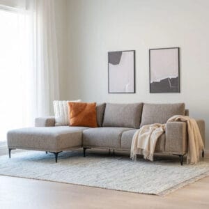 Asteri divaanisohva mocca-värissä vaaleassa olohuoneessa, sisustettu tyynyin ja viltillä