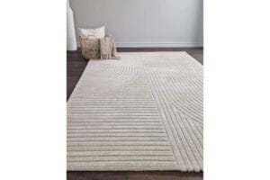 Suorakaiteen muotoinen beige Bella wilton-matto tummalla lattialla, kori ja viltti taustalla