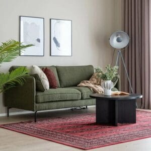 Punainen kuviollinen matto vihreän sohvan ja mustan pyöreän sohvapöydän alla modernissa olohuoneessa