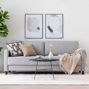 Vaaleanharmaa Luosto 3-istuttava vuodesohva olohuoneessa, päällä tyynyjä ja viltti – täydellinen pieni vuodesohva