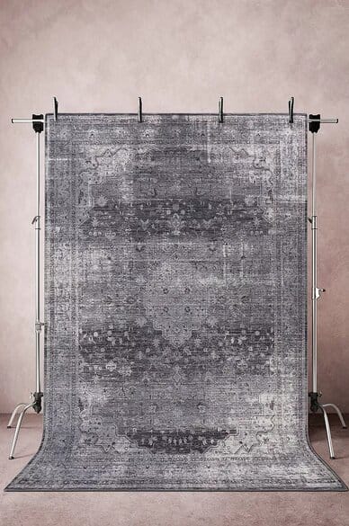 Jotex HERIS sileä matto 250x350 cm, harmaa kuviollinen matto ripustettuna telineeseen vaaleanpunaisella taustalla