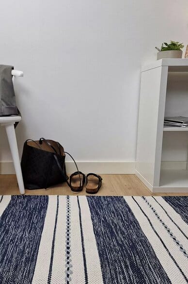 KM Home Sund -puuvillamatto eteisessä, sinivalkoinen raitakuosi, taustalla laukku ja sandaalit