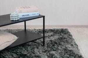 Natta vihreänharmaa nukkamatto ja musta sivupöytä modernissa sisustuksessa