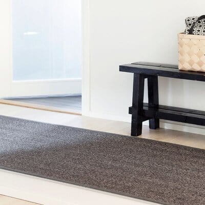 VM Carpet Barrakuda sisalmatto eteisessä, tumma sävy, musta penkki ja vaalea kori taustalla
