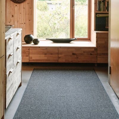 VM Carpet Duuri -matto antrasiitinharmaana eteisessä, ympärillä puupaneeliseinät ja ikkuna luonnonvalossa