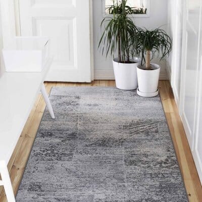 VM Carpet Rustiikki -matto harmaissa sävyissä valoisassa eteisessä, vieressä valkoisia kukkaruukkuja ja penkki