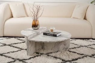 Mukund Freesia pyöreä marmori sohvapöytä pehmeän beigen sohvan ja graafisen nukkamaton kanssa