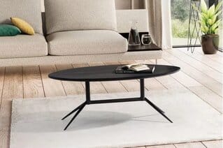 Moderni musta ovaali Wohnling-sohvapöytä massiivipuusta valkoisen maton ja beigen sohvan edessä