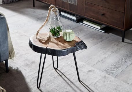 Pieni epäsymmetrinen puinen sohvapöytä mustilla metallijaloilla harmaalla puulattialla