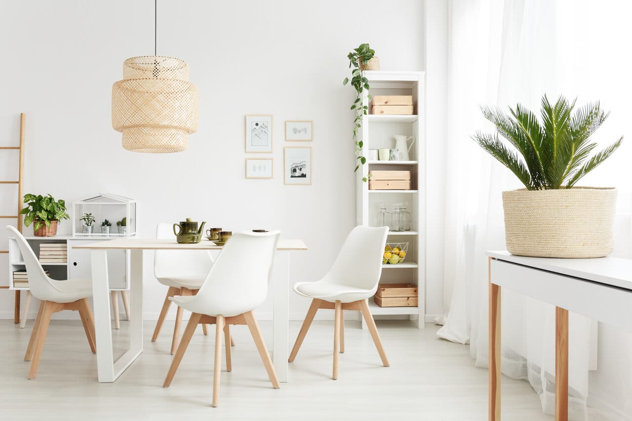 Vaalea ruokailutila, jossa on valkoinen ruokapöytä ja modernit valkoiset tuolit puujaloilla