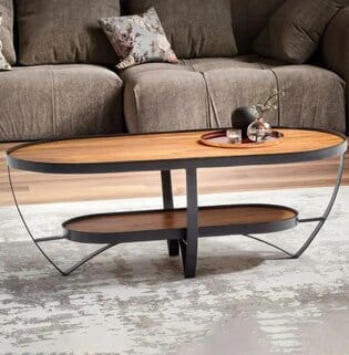 Ovaali sohvapöytä, jossa puinen kansi, musta metallirunko ja alahylly, ruskea sohva taustalla