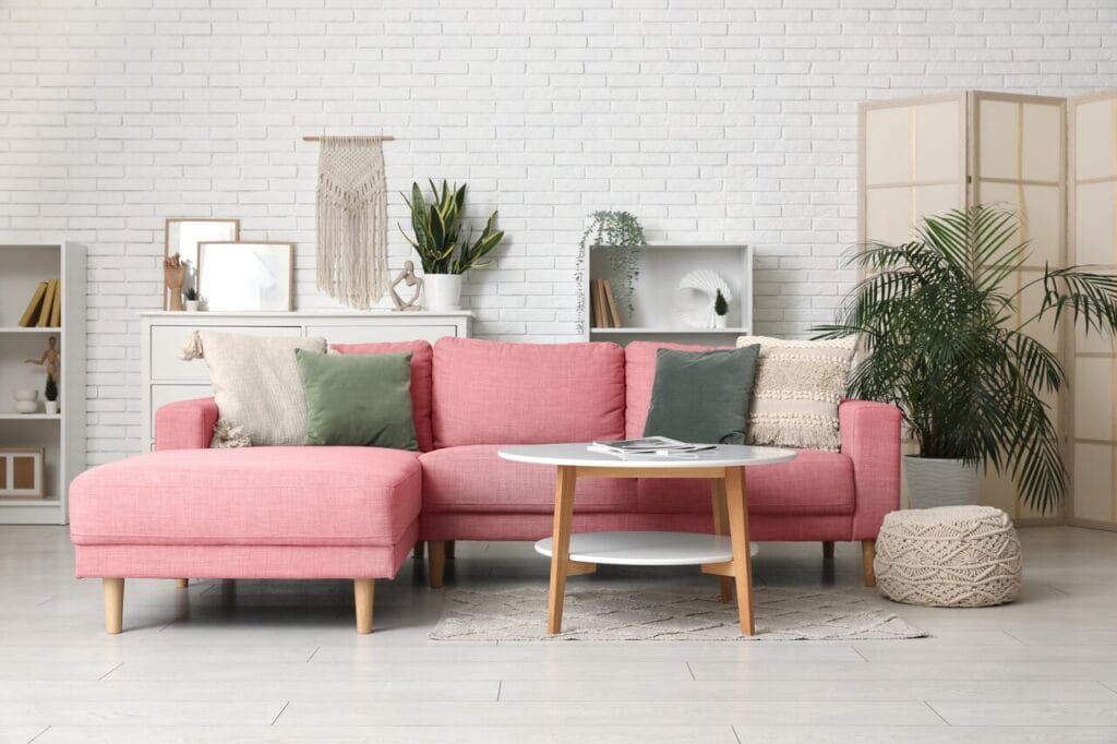 Vaaleanpunainen kulmasohva vaaleassa olohuoneessa, artikkelin kansikuva pinkeistä kulmasohvista.