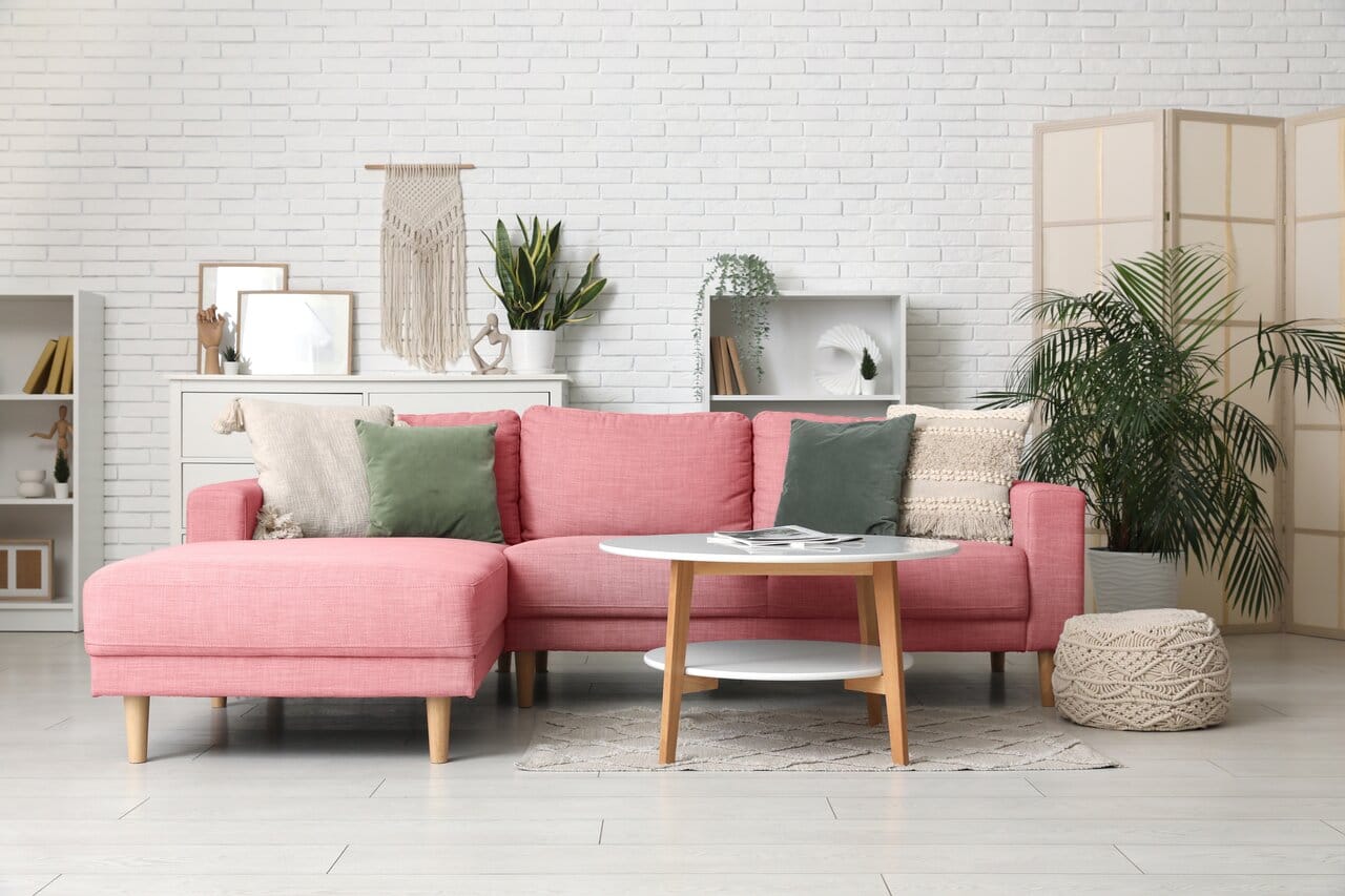 Vaaleanpunainen kulmasohva vaaleassa olohuoneessa, artikkelin kansikuva pinkeistä kulmasohvista.