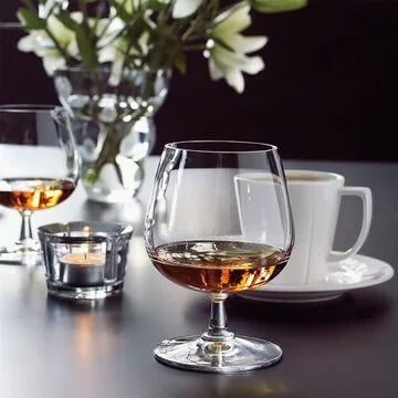 Konjakkilasi, jossa on meripihkanväristä konjakkia tyylikkäästi katetulla pöydällä.